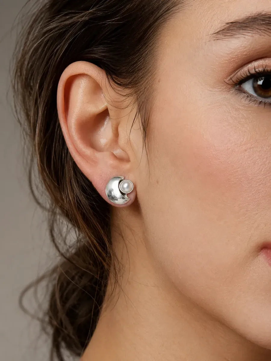 Broquel de perla natural de agua dulce de 1.4 cm colocado en la oreja para mostrar escala.